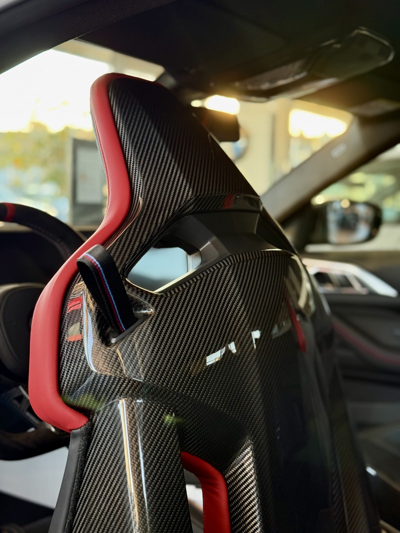 Detaliu scaun cu carbon lăcuit și piele roșie BMW M